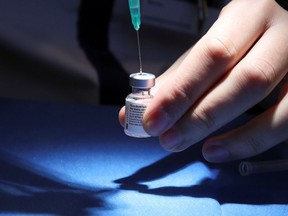 File: A medical worker fills a syringe with a dose of the Pfizer-BioNTech coronavirus vaccine.