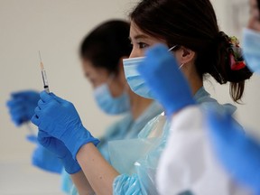 FILE: A health worker fills a syringe with a dose of the Pfizer-BioNTech coronavirus disease (COVID-19) vaccine.