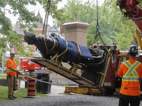 Emotions in the crowd were high as workers from Heritage Grade removed the statue of Sir John A. Macdonald from the pedestal in City Park and place it on a flatbed in Kingston, Ont. on Friday, June. 18, 2021.