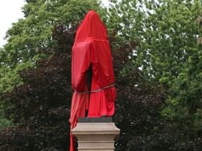 A statue of Canada's first prime minister, Sir John A. Macdonald is shrouded by Indigenous supporters at City Park in Kingston on Friday, June 11, 2021, to protest issues related to residential schools.