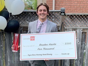 Kingston Frontenacs defenceman Braden Hache with his Hockey Gives Blood award and bursary cheque at his home in Newmarket on Wednesday.