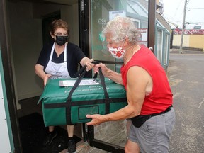 Volunteer driver Gerard Bondt accepts a meal bag from Colleen Labelle, Martha's Table program co-ordinator for their meal delivery service on Tuesday June 8, 2021. Martha's Table received a grant of $97,500 grant from the Ontario Trillium Foundation to continue the service.