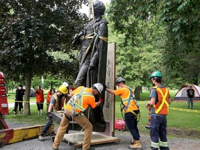 Work crews set the statue of Sir John A. Macdonald down during its removal from City Park in Kingston on Friday.