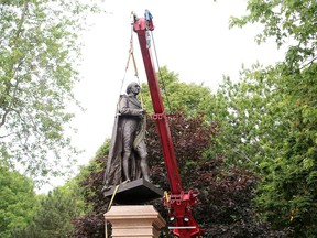 The statue of Sir John A. Macdonald is lifted off its pedestal in City Park in Kingston on Friday.