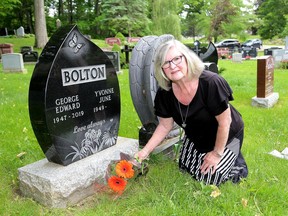 Yvonne Bolton, kneels by her husband's grave at the Cataraqui Cemetery on Monday June 7, 2021. Bolton complained about personal items being removed from around graves at the cemetery.