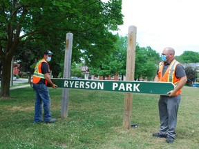 Larry Gill, left, Owen Sound's parks and cemetery supervisor, and Adam Parsons, manager of parks and open space, remove the wooden Ryerson Park sign Tuesday. The park on 8th Street East bears the name of a key architect of Canada's residential school system. DENIS LANGLOIS