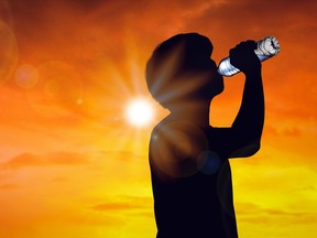 Silhouette man is drinking water bottle on hot weather background with summer season. High temperature and heat wave concept.

Model Released (MR)