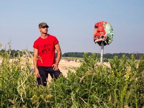 Skyler Williams poses for a photo with the head from a statue of Egerton Ryerson that was removed from Ryerson University,  at 1492 Land Back Lane reclamation camp in Caledonia.