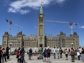 People gather as drummers perform at the Residential Schools Memorial of shoes at the Centennial Flame on Parliament Hill in memory of the 215 children whose remains were found at the grounds of the former Kamloops Indian Residential School in Kamloops, B.C.