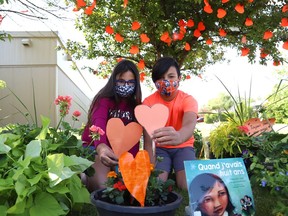 Leah Aubertin, 9, and her brother, Xavier, 11, place hearts in a flower pot at the Garden of Hearts ceremony at Ecole publique Franco-Nord in Azilda, Ont. on Friday, June 4, 2021. The ceremony was held to commemorate the 215 children whose remains were found at a former residential school in Kamloops, BC. School representatives placed 215 orange hearts in front of the school. John Lappa/Sudbury Star/Postmedia Network