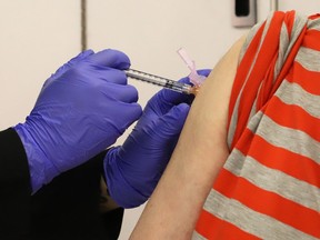 A registered pharmacy technician administers a shot at a COVID-19 vaccination clinic at the Real Canadian Superstore in June.