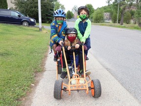 Davis Armstrong, 9, middle, gives Lex Armstrong, 6, left, and Gabriel Dion, 5, a ride in Copper Cliff, Ont. on Tuesday June 22, 2021. John Lappa/Sudbury Star/Postmedia Network