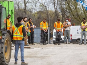 Workers pause for a moment of silence on April 28 at 555 Teeple Terrace in London, Ont. where two workers lost their lives last December and five were injured. Mike Hensen/Postmedia Network