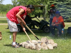 Tyson Nahdee tends to a sacred fire on May 31 near the Walpole Island First Nation monument honouring the children from the community who attended Indigenous residential schools. The fire was for the 215 children whose bodies were found recently at the site of a former residential school in Kamloops, B.C. Mark Malone