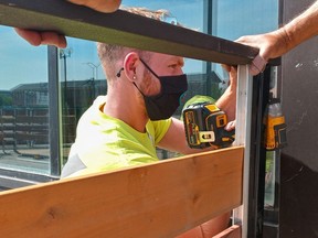 Jaxon Dougan of Hamilton installs a pop-up patio on the sidewalk in front of St. Thomas Roadhouse.Eric Bunnell