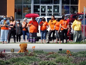 Kenora residents adorned in orange shirts line the sidewalk at a memorial for the 215 Indigenous children discovered in a mass grave at a former residential school near Kamloops, B.C. in downtown Kenora on Monday, May 31. Bronson Carver/Miner and News