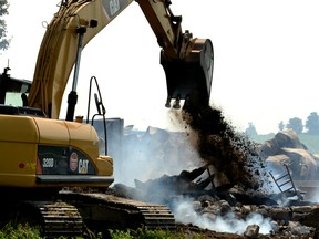 A backhoe buries some remaining hot spots and flare-ups at the scene of a suspicious house and barn fire on a vacant property west of Gowanstown in North Perth Monday morning. Galen Simmons/The Beacon Herald/Postmedia Network