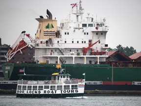 Soo Locks Boat Tours passes by bulk carrier Cinnamon entering Soo Locks in Sault Ste. Marie, Mich., on Tuesday, July 6, 2021. (BRIAN KELLY/THE SAULT STAR/POSTMEDIA NETWORK)