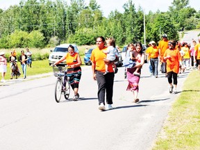 from left to right, Allison Abitong, Michael Eshkawkogan carrying his son, wife Rachel carrying her daughter with supporters following moments before completing the run.