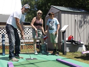 Don Larivee enjoys a little warm weather while waiting to line up a putt at the Mini Putt/Batting Cages in Hollinger Park on Friday afternoon. Looking on are his wife Patricia Larivee, along with his grandson Hayden Hebert. The weekend weather calls for a mix of sun and cloud both Saturday and Sunday, with a high of 27 C both days. RICHA BHOSALE/THE DAILY PRESS