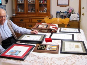 Second World War veteran Austin Fuller looks at a table covered with certificates of appreciation and other recent honours he's received.