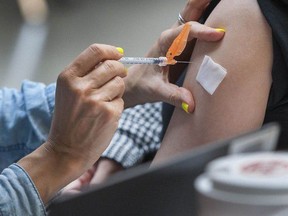 A health nurse vaccinates a person at a clinic.
