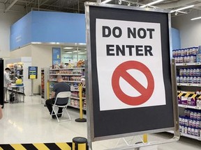 Three people wait in the recovery area following their COVID-19 vaccinations at the Superstore on Baseline Road in Sherwood Park. Photo by Lindsay Morey / Postmedia.