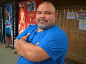 Juan Hernandez, foreground, has been ordered by the city to dismantle a wooden shelter and permanently remove seven vending machines from his home's driveway or apply alternatively for a rezoning application by Aug. 30. Fernandez said he will apply. DEREK BALDWIN