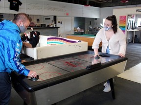 Seth Compton, left, and Emma St. John enjoy a game of air hockey at OutLoud, Tuesday. The centre was broken into Tuesday morning, and thieves made away with about $1,000 worth of goods.
PJ Wilson/The Nugget