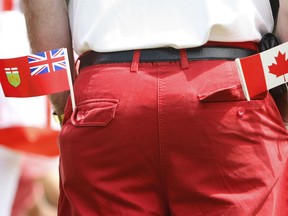A man keeps an Ontario flag in one pocket and a Canadian one in the other during the Canada Day celebrations.