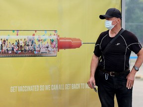 A transit passenger waits for their bus beside a COVID-19 vaccination advertisement in Edmonton on Saturday, July 17, 2021. As of Monday, July 26, Alberta Health reported eight active cases in Strathcona County — two cases in Sherwood Park and six in the rural portion of the county. DAVID BLOOM/Postmedia