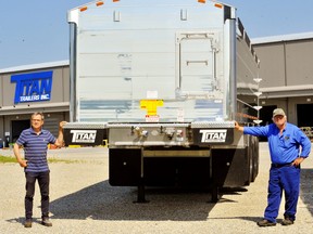 Titan Trailers of Courtland ships numerous custom-built trailers to western Canada, so owner Mike Kloepfer, right, has decided to load them with fresh-cut hay for livestock producers in Manitoba, Saskatchewan, and Alberta who are struggling with a drought-induced shortage. The first shipment headed west Monday. At left is Dan Cohoe, a special projects manager with Titan Trailer.