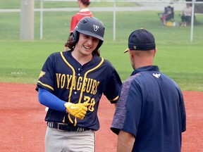 Nicholas Signorile (28) of the Sudbury Voyageurs celebrates a hit with first-base coach Jean-Gilles Larocque during Premier Baseball League of Ontario 16U action at Terry Fox Sports Complex in Sudbury, Ontario on Sunday, July 25, 2021.