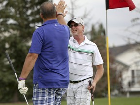 Chris MacConnell (right) and Vic Klassen from The Hamlets at Cedarwood Station high five each other after MacConnell sinks a putt in the Airdrie Chamber of Commerce Golf Classic at Woodside Golf Course on Friday August 14, 2015 in Airdrie, Alta. The annual fundraising tournament will benefit the Chamber and the Airdrie Health Foundation to support local health programs, education, facilities and equipment. Britton Ledingham/Airdrie Echo/Postmedia Network
