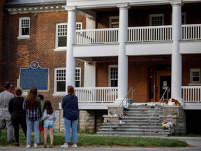 People stand in front of the main entrance of the Mohawk Institute, a former residential school in Brantford, where a makeshift memorial honours the remains recently discovered in unmarked graves at the former Kamloops, B.C., Indian Residential School. The St. Marys museum is offering a guided tour of the former school Friday. (COLE BURSTON/AFP via Getty Images)