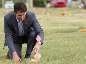 Prime Minister Justin Trudeau places a teddy bear at an unmarked grave on Cowessess First Nation, where a search had found 751 unmarked graves from the former Marieval Indian Residential School near Grayson, Saskatchewan, July 6, 2021.