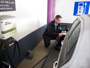 Eric MacNaughton, demonstrates one of Calgary's City Hall parkade electric vehicle charging stations on Thursday March 23, 2017.   Gavin Young/Postmedia Network
