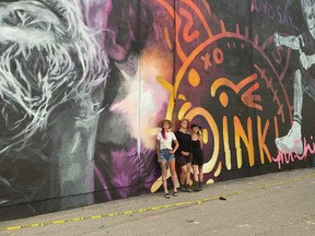 Artists Layla Folkmann, Lacey Jane and their assistant Hannah McMillan stand in front of their mural of Ken Chinn, better known as Mr. Chi Pig, the frontman fro SNFU, which is  painted on the east side of The Buckingham at 10439 82 Avenue NW. Photo Supplied