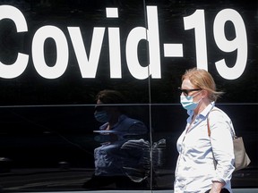 A woman wearing a mask passes by a coronavirus disease mobile testing van, as cases of the infectious Delta variant of COVID-19 continue to rise, in Washington Square Park in New York City.