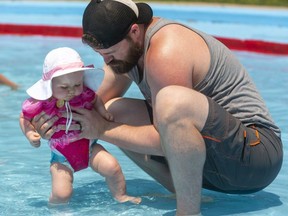 Tristan Vanschip helps his eight-month-old daughter, Aurora, walk in Springbank Park wading pool on Monday, July 5, 2021. All city wading pools opened Monday, with Springbank being the busiest. (Mike Hensen/The London Free Press)