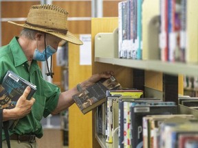 Steve Humphries picks up some summer reading at the Central Library on Thursday. The London Public Library reopened its 12 branches this week at 25 per cent capacity with 45-minute time limits for visitors. (Mike Hensen/The London Free Press)