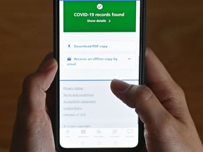 An illustration picture shows a smartphone screen displaying a Covid-19 vaccine record on the National Health Service (NHS) app in London on May 18, 2021. (Photo by JUSTIN TALLIS / AFP)