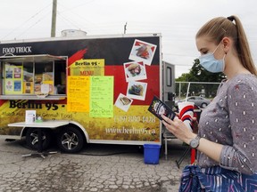 Belleville's Diandra Van Oosten holds a lemonade while reading the Curbside Culture guidebook and waiting for her lunch order during the event's Carnival Treats portion at the former city fairground. The location was limited to the weekend but other locations are serving food all summer long.