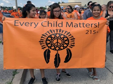 Three girls hold a banner to help lead the Unity Walk on Thursday in Brantford from the civic centre to the former Mohawk Institute residential school. Susan Gamble