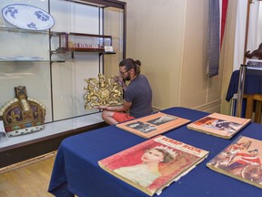 Nathan Etherington, program and community coordinator at the Brant Museum and Archives places a royal crest in a display case on Tuesday in Brantford, Ontario. The museum will reopen Friday and will feature a new exhibit of Royal Visits to Brantford, including one by the Prince of Wales in 1860.