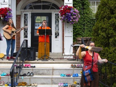 ALPHA band members Angel Kelsey, left, and Donna Lynn Neil perform on the front steps of Gananoque Town Hall on Canada Day in remembrance of the more than 1,100 unmarked gravesites found across Canada, while Clarice Gervais smudges those who want to be cleansed.