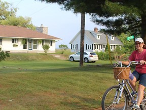 Karen Benoit enjoys a bike ride along Lakeshore Road in Rondeau Provincial Park where the majority of cottages are located. The province is considering selling the cottage lots that have been leased for more than a century. PHOTO BY Ellwood Shreve/Postmedia Network