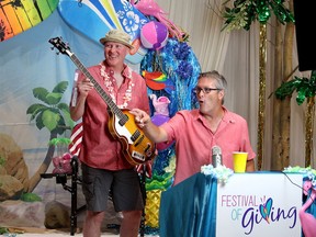 Auctioneer Greg Hetherington announces a $4,000 winning bid for a Paul McCartney guitar, being held by volunteer Matt Nicholson, during the live auction of the annual Festival of Giving held Saturday. Ellwood Shreve/Postmedia Network