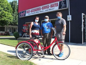 Mike Mariash, middle, had tears of joy when he picked up his new trike from Smith Cycle, thanks to his friend and co-worker Ashley Tennant, left, rallying the community through a GoFundMe campaign to replace the trike that had been stolen on Mariash's birthday. Rob Smith, right, an employee from Smith Cycle, got the trike assembled for Mariash. PHOTO BY Ellwood Shreve/Chatham Daily News