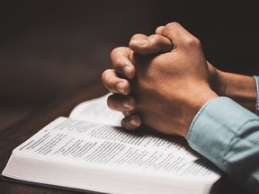 Man praying with his hands on a bible in church.  Man praying with his hands on a bible. Javier_Art_Photography/Cornwall Standard-Freeholder/Postmedia Network